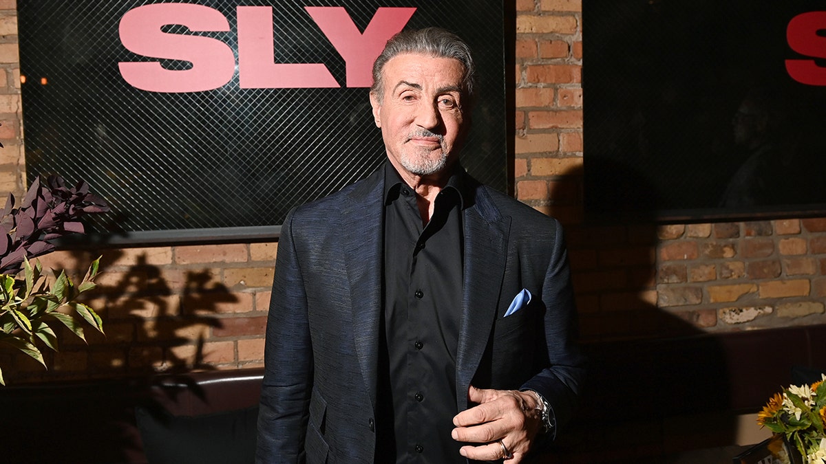 Sylvester Stallone em uma jaqueta justa no tapete e uma camisa preta parece elegante