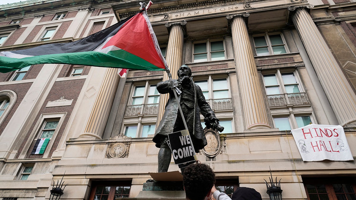 A student protester parades a Palestinian emblem extracurricular nan entranceway to Hamilton Hall connected nan field of Columbia University