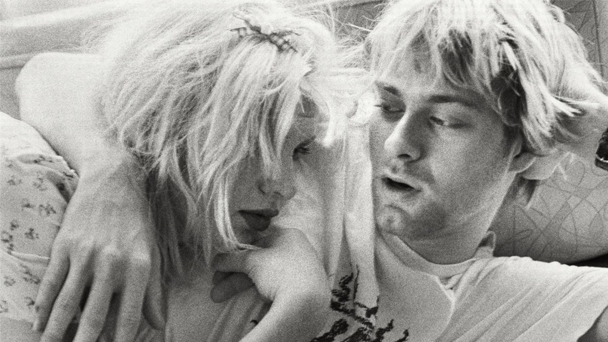A black and white photo of Kurt Cobain and Courtney Love hugging