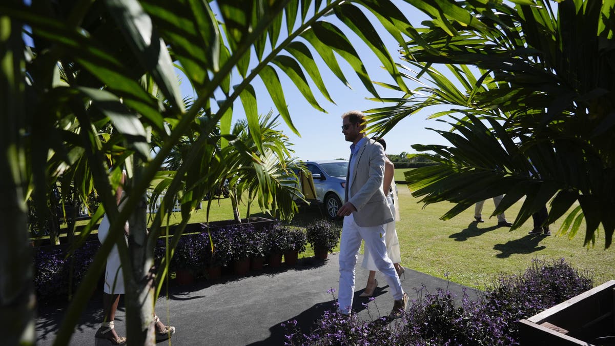 Prince Harry and Meghan Markle walking together wearing white.
