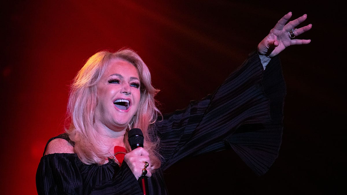 Bonnie Tyler singing on stage with her arm in the air