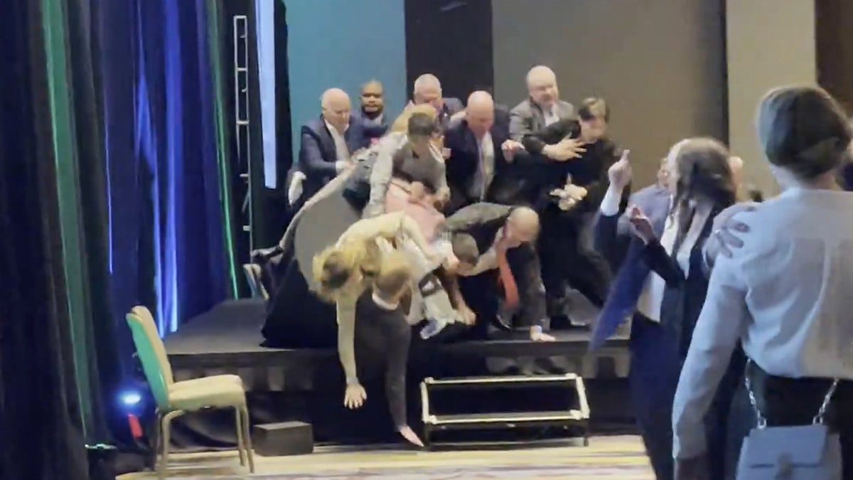 Activists with the group Climate Defiance topple off the stage while protesting Sen. Lisa Murkowski at a gala on Thursday.