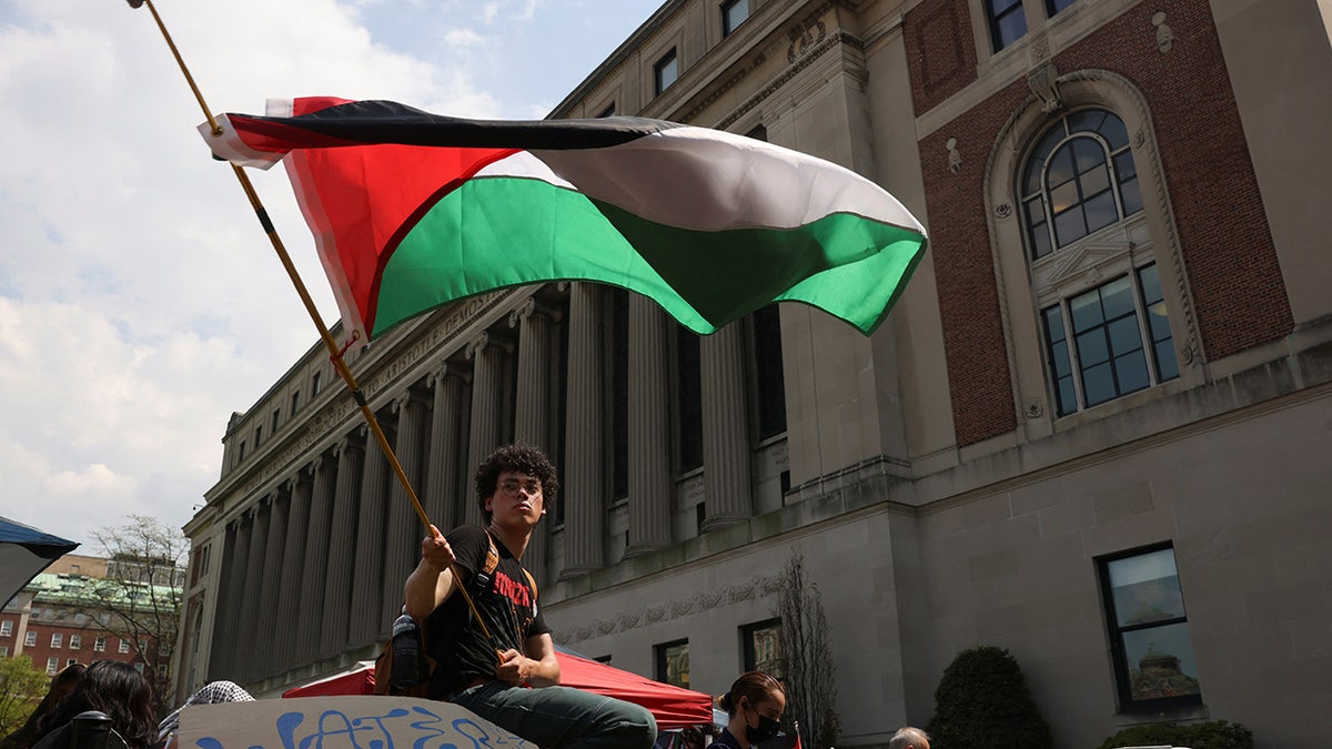 A student waves a flag during a march on Columbia University campus in support of a protest encampment supporting Palestinians