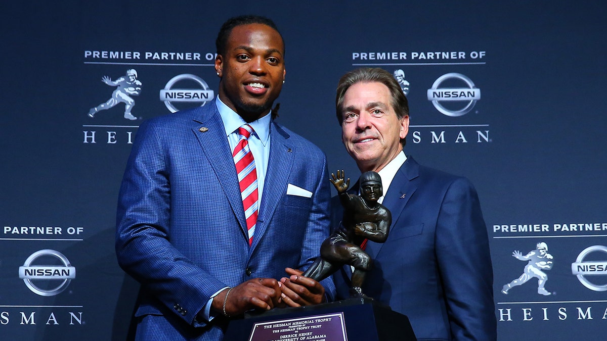 Derrick Henry and Nick Saban pose with Heisman Trophy