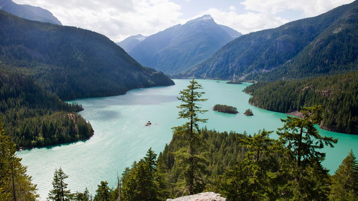 Sunlight reflects off the blue surface of Diablo Lake, which sits at the foot of mountains in Washington's North Cascades National Park