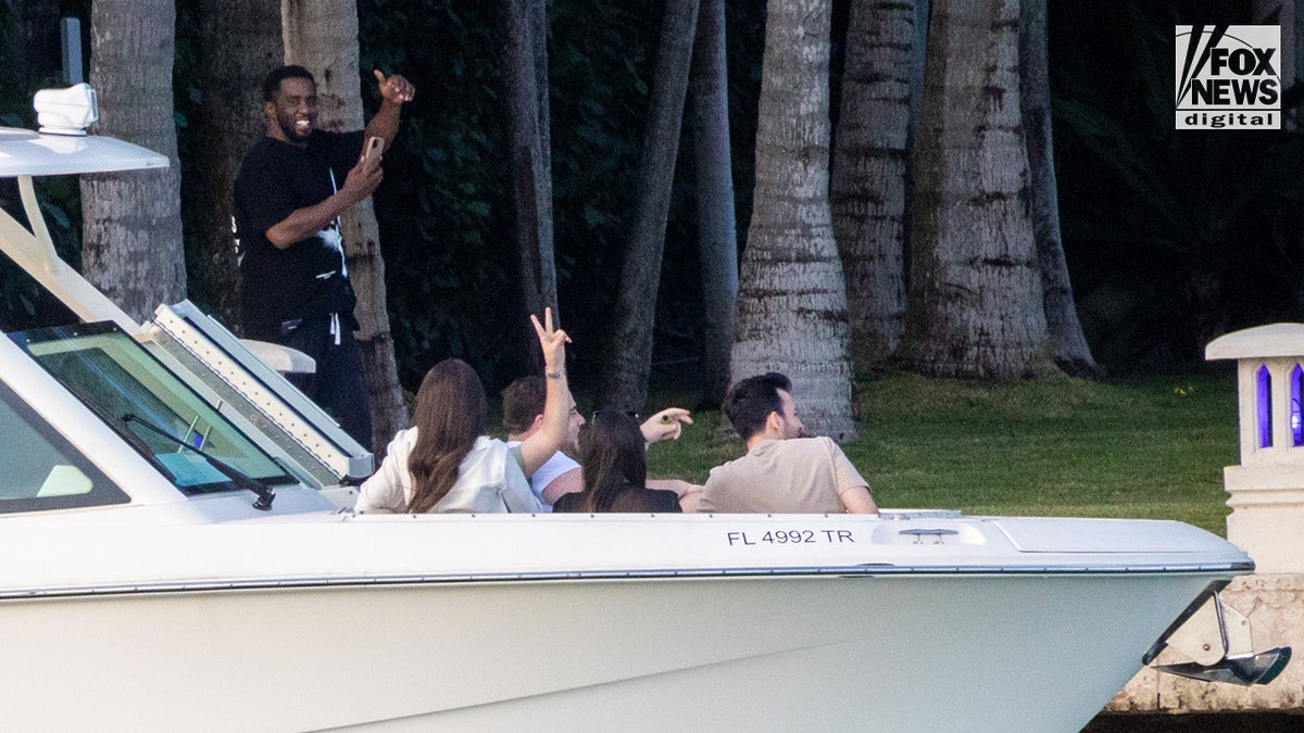 Sean "Diddy" Combs waves to boaters as they pass by his Star Island home in Miami Beach, Florida
