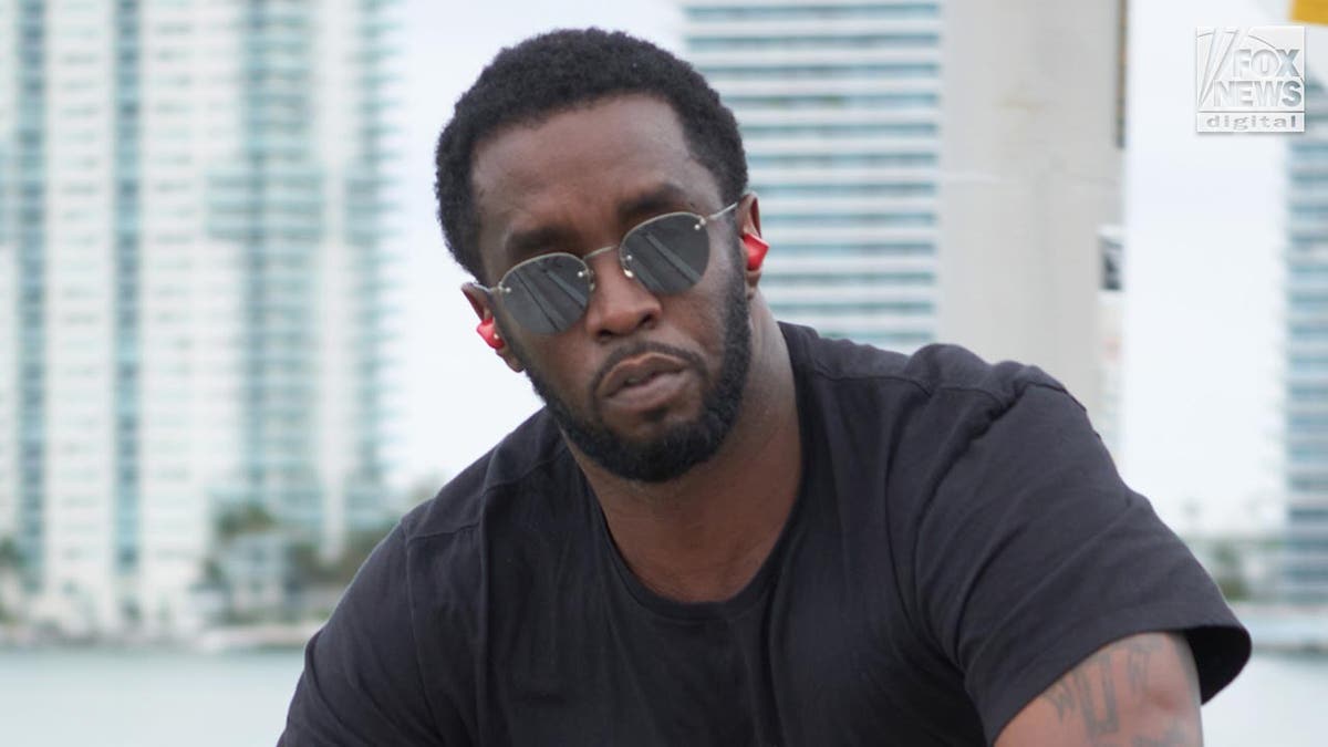 P Diddy looks at the camera wearing sunglasses while riding his bike.