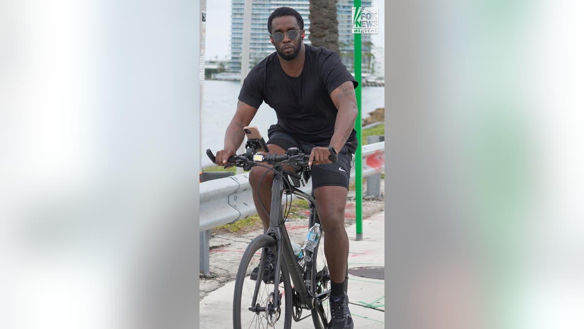 P Diddy looks at the camera wearing sunglasses as he rides his bicycle.