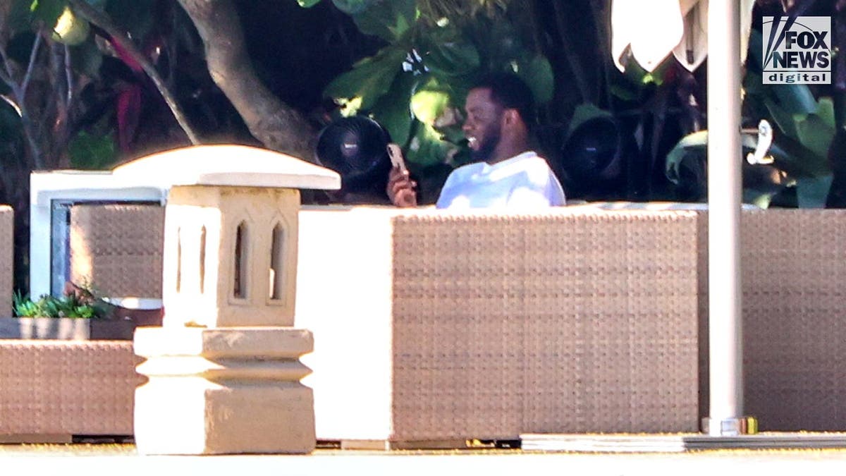 Sean "Diddy" Combs sits on his couch outside his Star Island talking into his phone