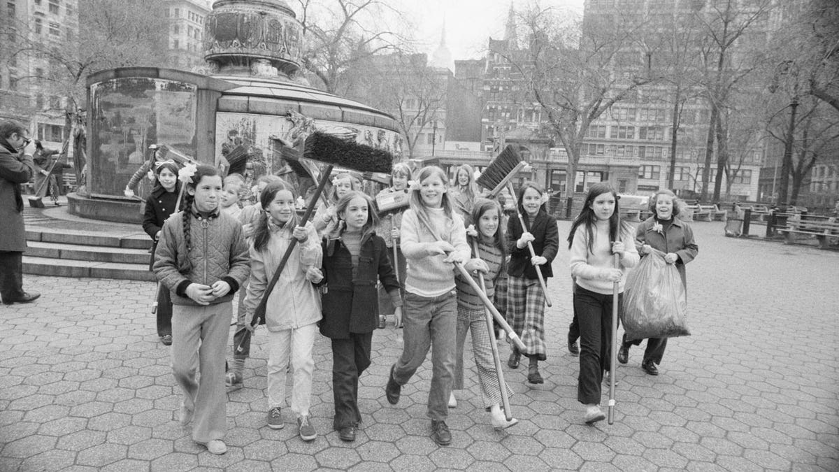 A group of girls carries brooms done a parkland connected nan first Earth Day successful New York City arsenic they caput for nan area they were assigned to cleanable up.