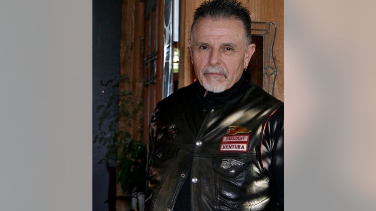 George Christie standing up wearing a black leather jacket