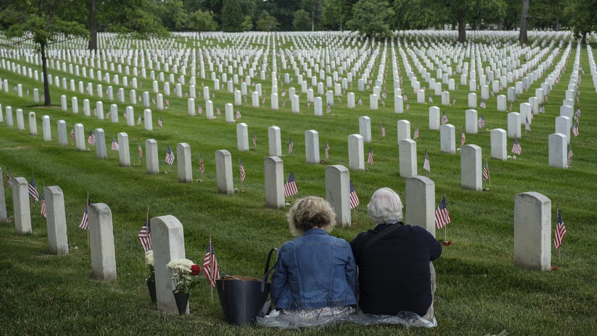 Two people sit in a cemetery