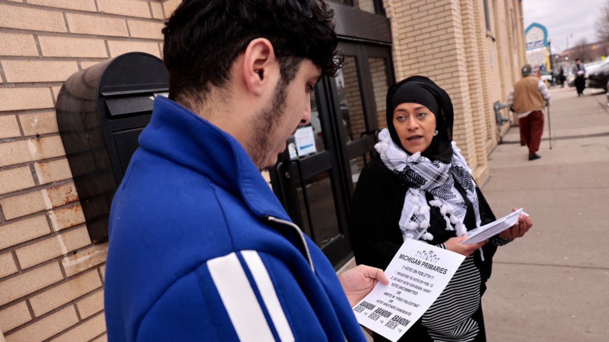 man receives political flier from woman outside mosque