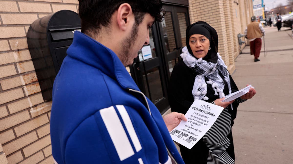 man receives political flier from woman outside mosque