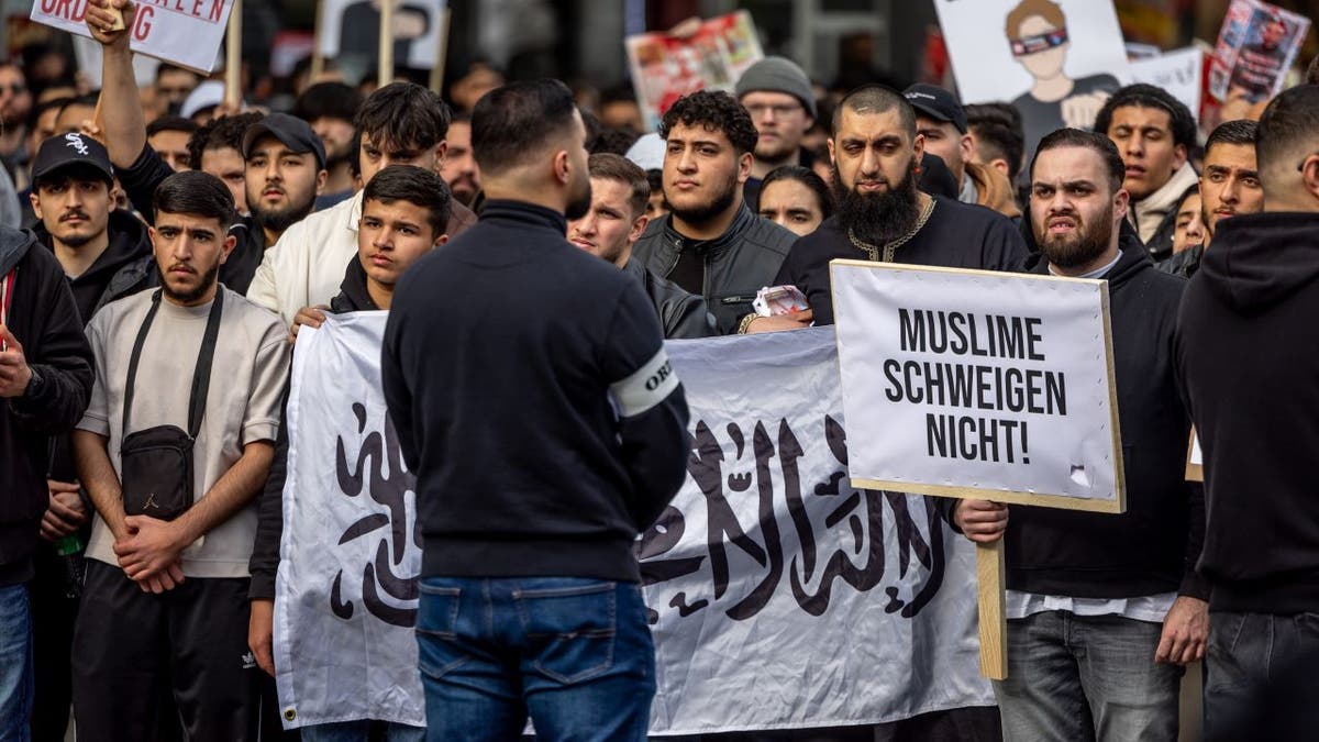 Protesters standing behind Arabic flag