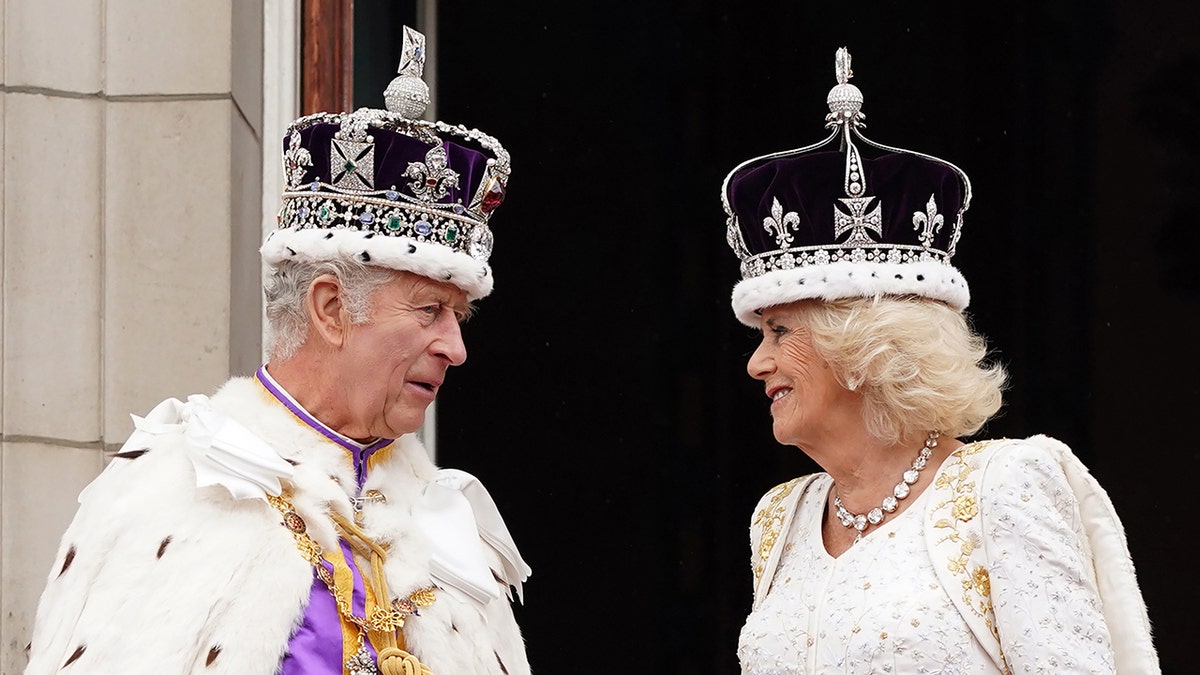 King Charles and Queen Camilla in royal regalia looking at each other while wearing crowns.