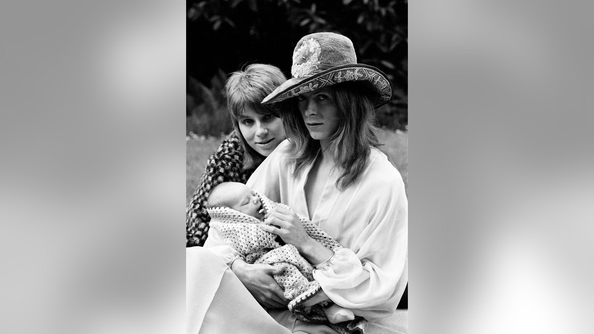 David Bowie holding onto his son sitting next to his wife Angie