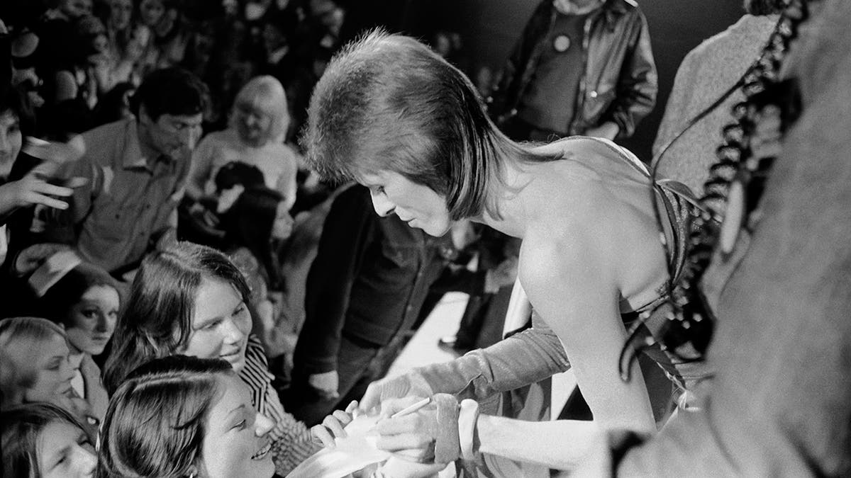 David Bowie greeting an excited young fan from the audience