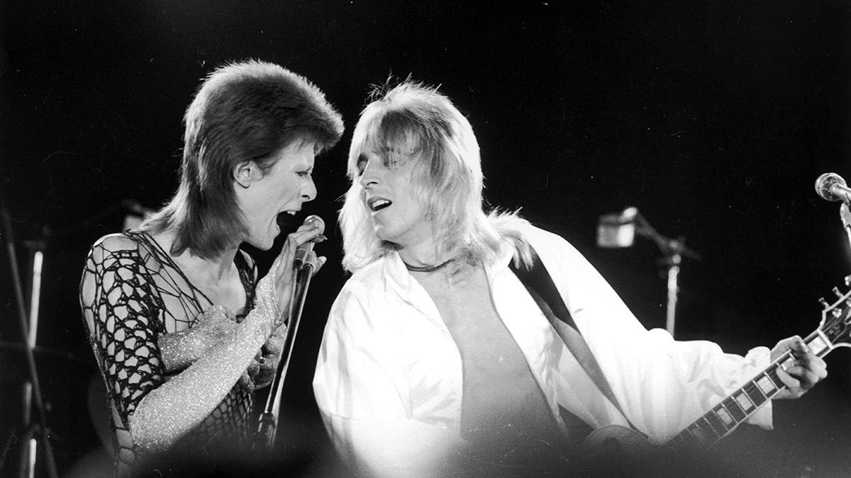 David Bowie singing to Mick Ronson as he plays the guitar
