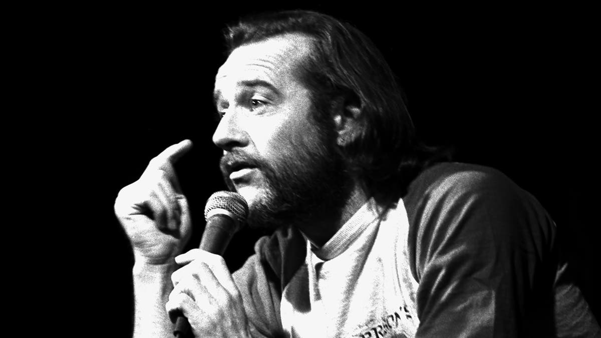 A close-up of George Carlin speaking to a mic
