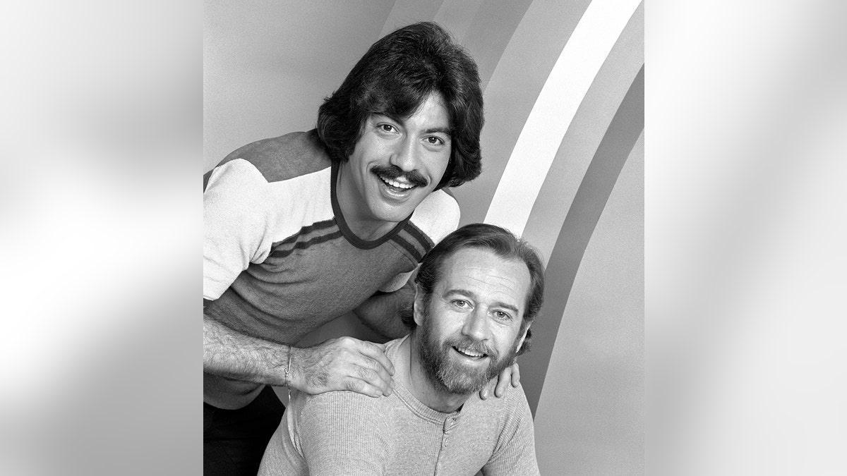 Tony Orlando standing behind George Carlin with his hands on Carlins shoulders