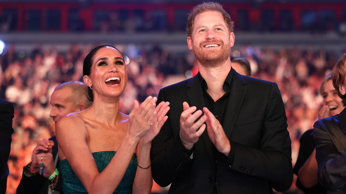 Meghan Markle and Prince Harry applauding while looking up