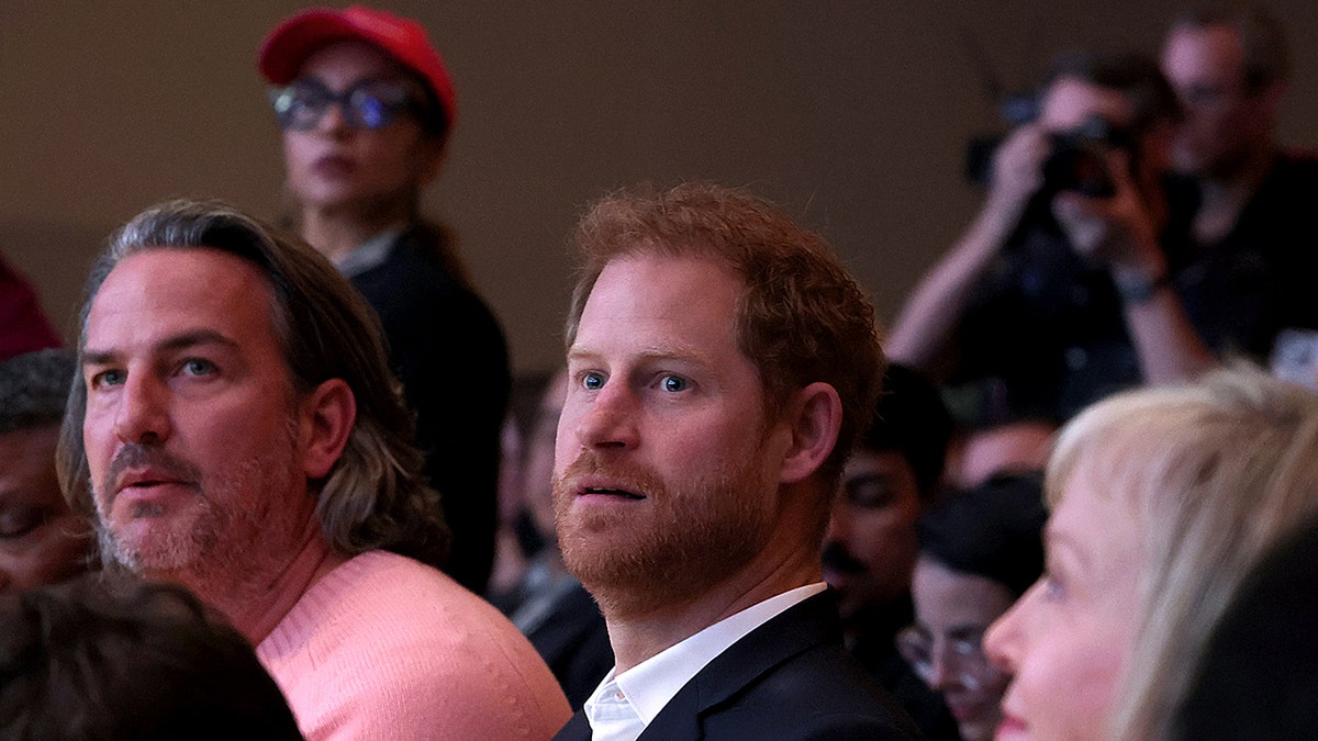 Prince Harry looking to the side in the center of a crowd