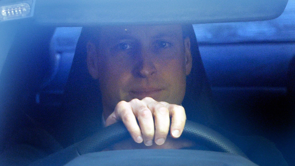 A close-up of Prince William driving his car.