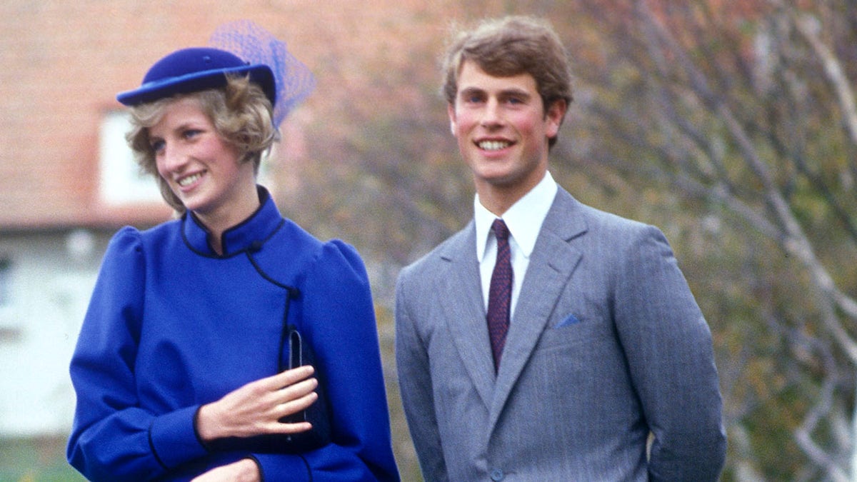 Princess Diana in a bright blue dress smiling next to Prince Edward in a suit and tie