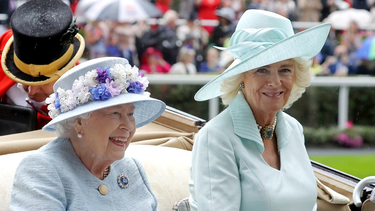 Camilla successful a oversea greenish outfit and matching chapeau sitting successful a carriage adjacent to Queen Elizabeth II