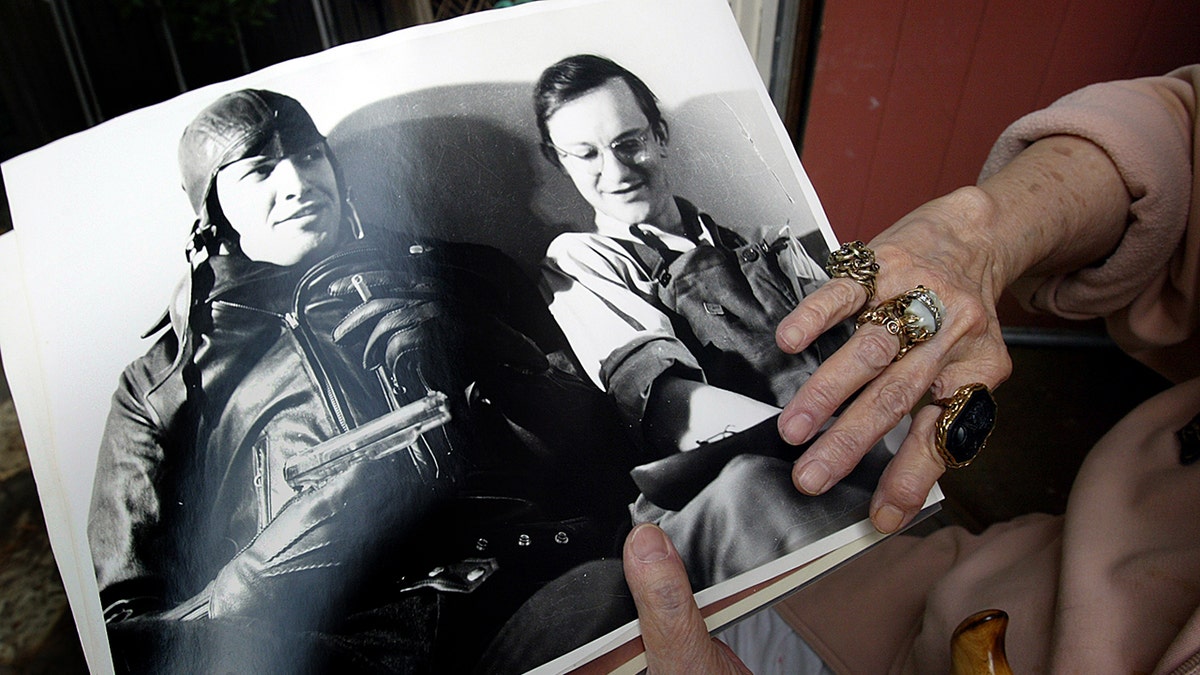 A viúva de Wally Cox segurando uma foto de Wally Cox sentado ao lado de Marlon Brando
