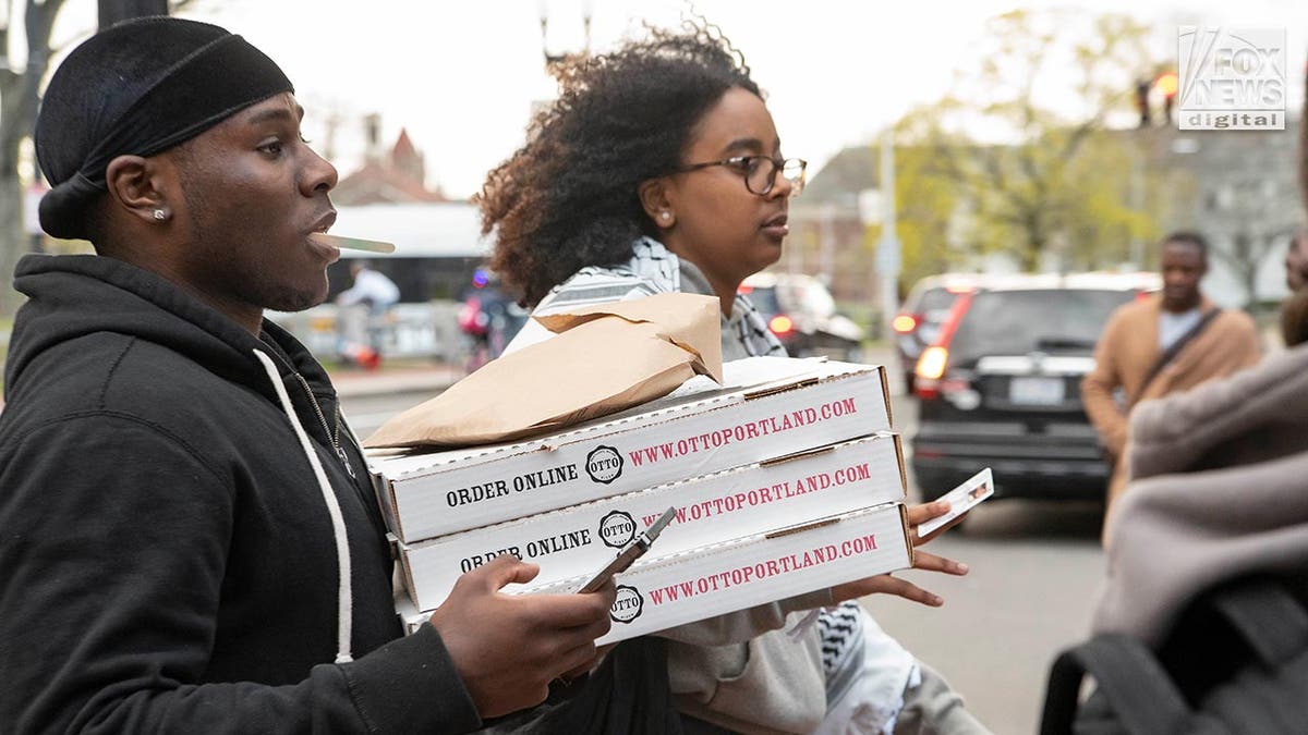 Students carrying boxes of pizza onto nan campus.