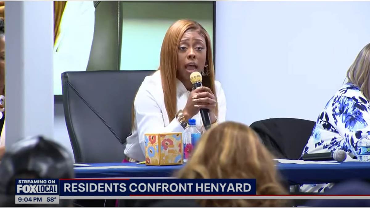 Henyard holding a microphone at a meeting