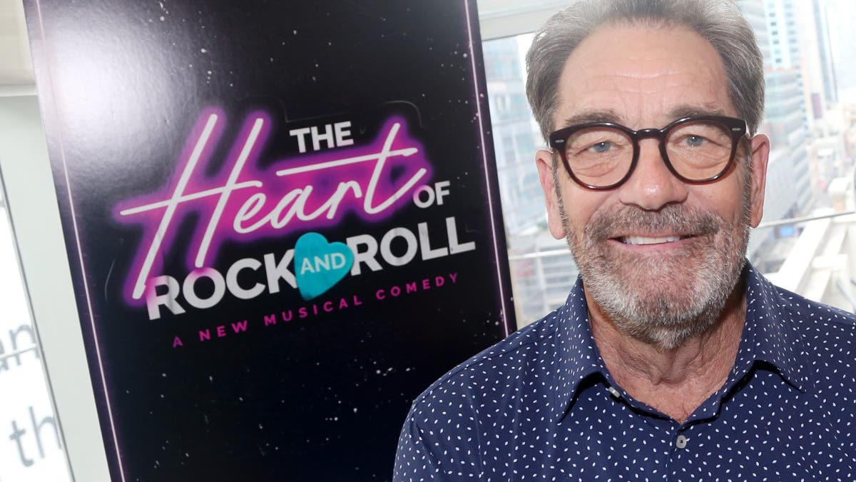 Huey Lewis standing in front of a sign for his musical