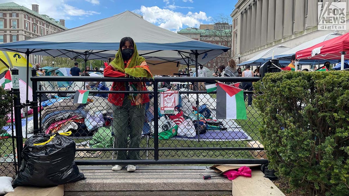 Masked protester standing behind gate