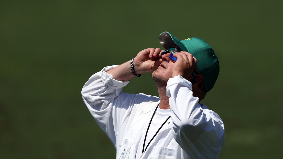 Masters caddie looks up at solar eclipse