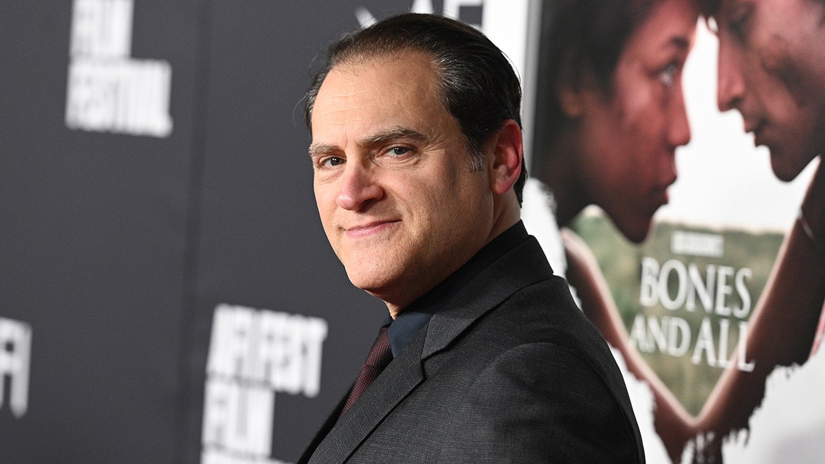 Michael Stuhlbarg looks at the camera from his side on the carpet