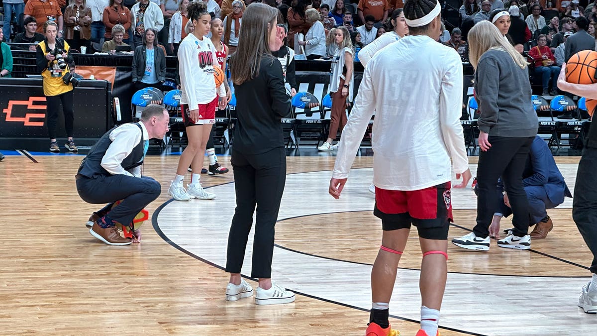 A person measures the 3-point line as North Carolina State warms up before an Elite Eight college basketball game against Texas in the women's NCAA Tournament