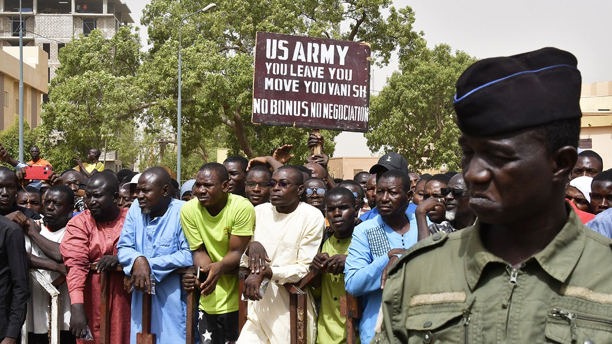 Protesters gather as a man holds up a sign demanding that soldiers from the United States Army leave Niger without negotiation during a demonstration in Niamey, on April 13, 2024. Thousands of people demonstrated on April 13, 2024, in Niger's capital, Niamey, to demand the immediate departure of American soldiers based in northern Niger, after the military regime said it was withdrawing from a 2012 cooperation deal with Washington. 