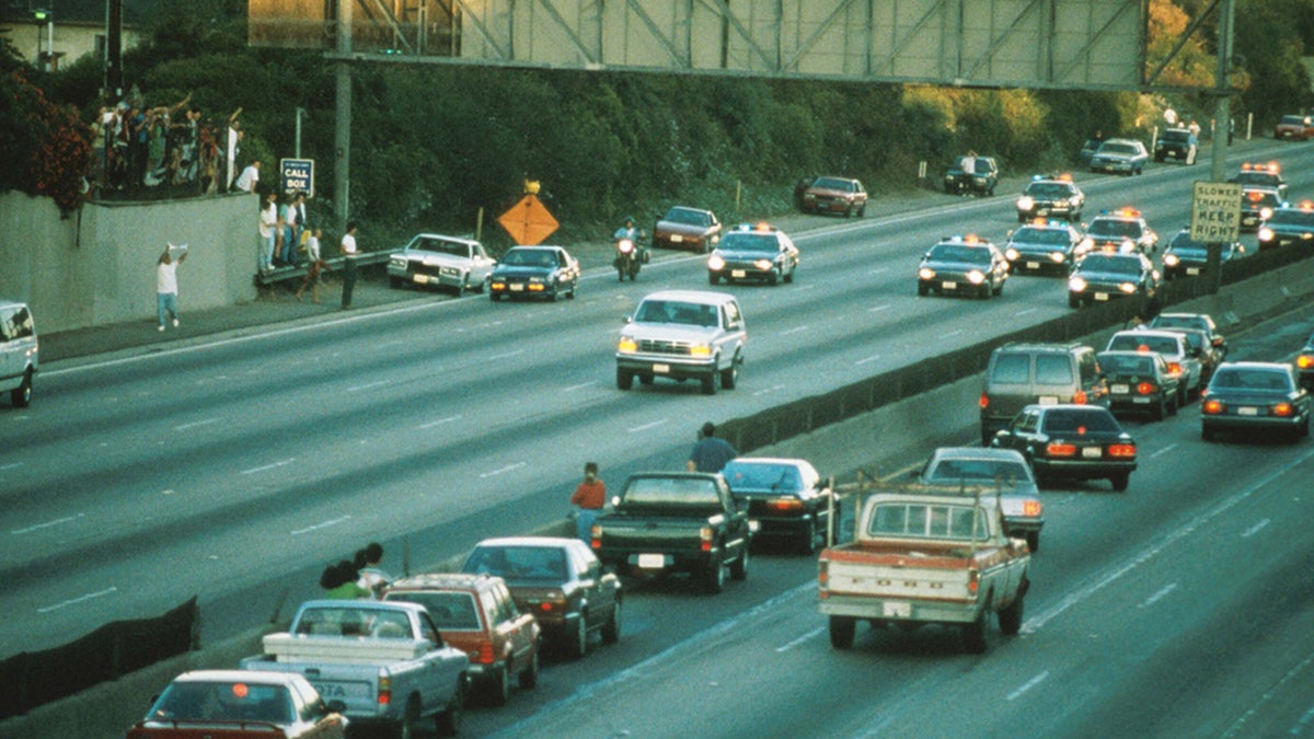 Motorists stop and wave as police cars pursue the Ford Bronco driven by Al Cowlings, carrying fugitive murder suspect O.J. Simpson