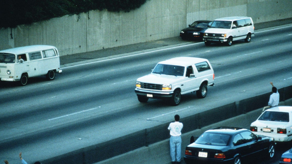 Motorists wave as police cars pursue the Ford Bronco driven by Al Cowlings, carrying fugitive murder suspect O.J. Simpson