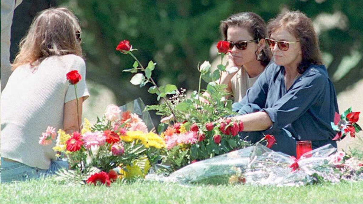 Murder victim Nicole Brown Simpson's mother Juditha, and sisters Denise and Tanya sit next to her grave surrounded by flowers