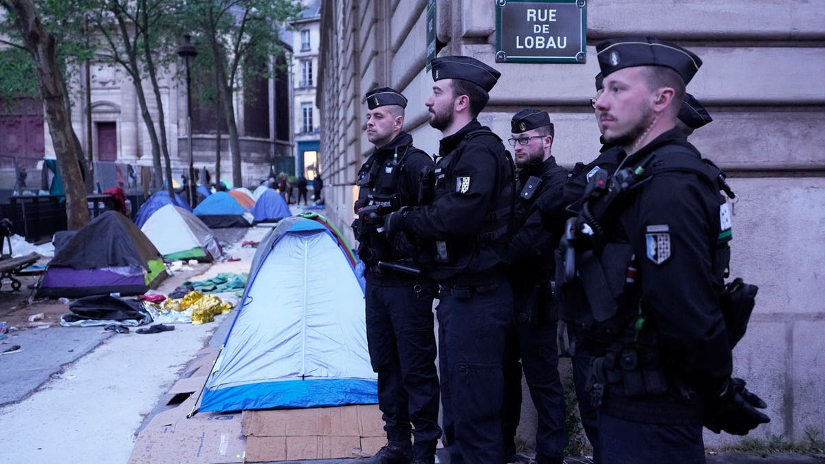 French police officers stand by a makeshift camp during an evacuation operation