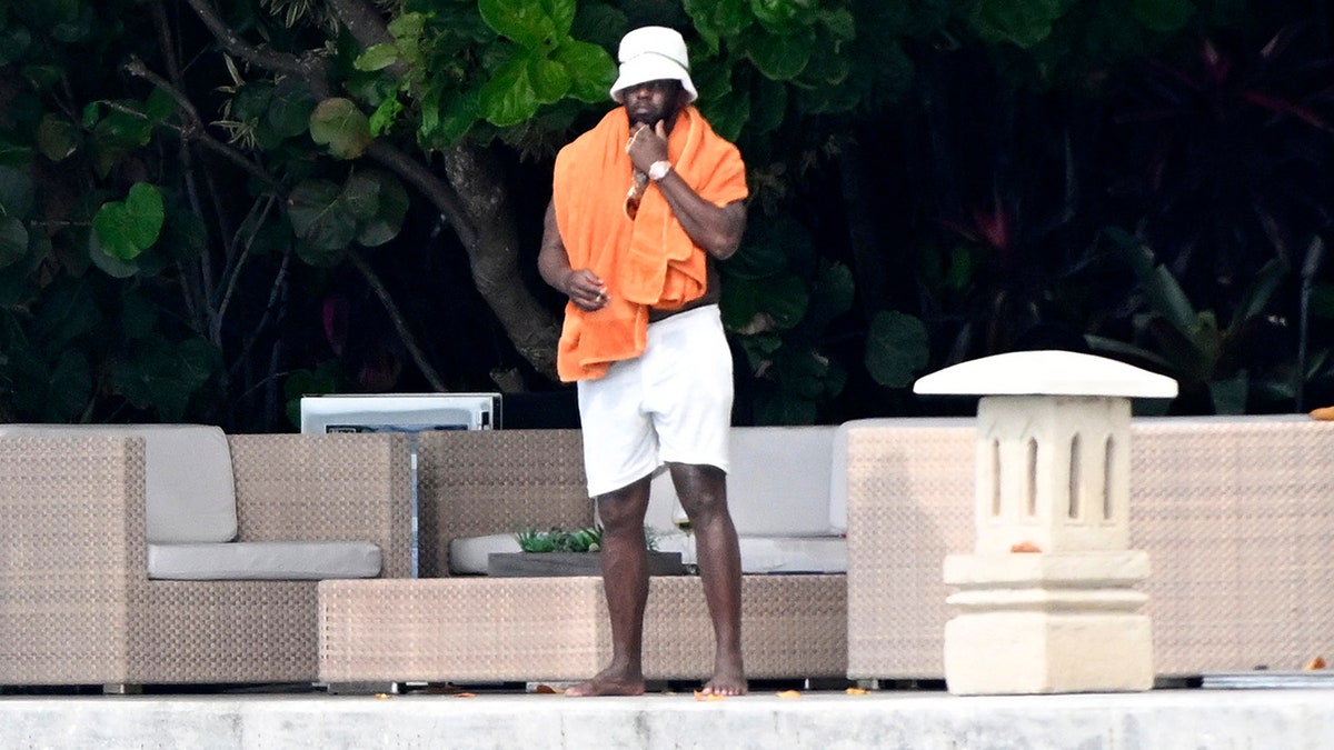 P Diddy is on his waterfront spot at his home in Miami with an orange towel draped over his shoulders