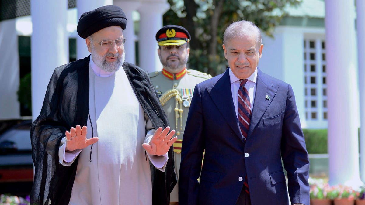 Iranian President Ebrahim Raisi walks with Pakistan's Prime Minister Shehbaz Sharif during a welcome ceremony