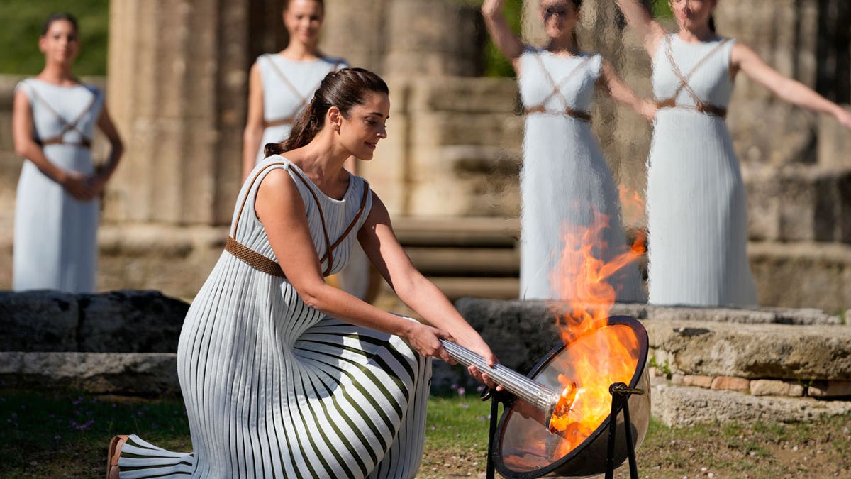 Greek actress Xanthi Georgiou, playing the role of the High Priestess, lights the torch during the lighting of the Olympic flame at Ancient Olympia site, birthplace of the ancient Olympics in southwestern Greece Oct. 18, 2021.
