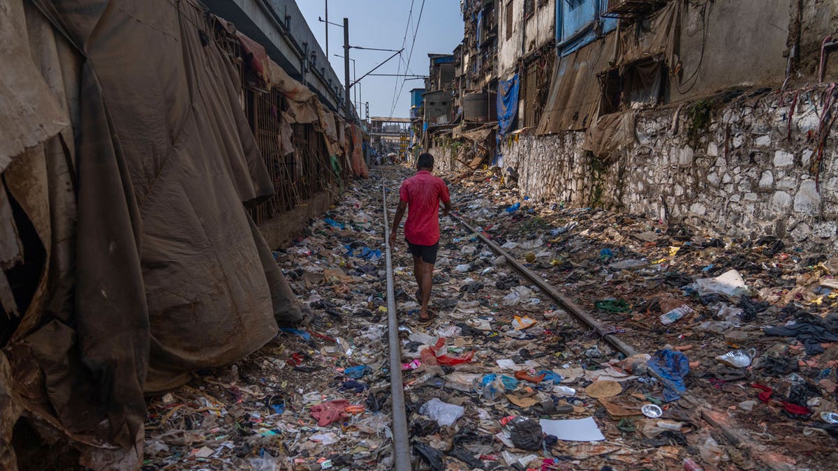 A man walks connected a railway way littered pinch plastic