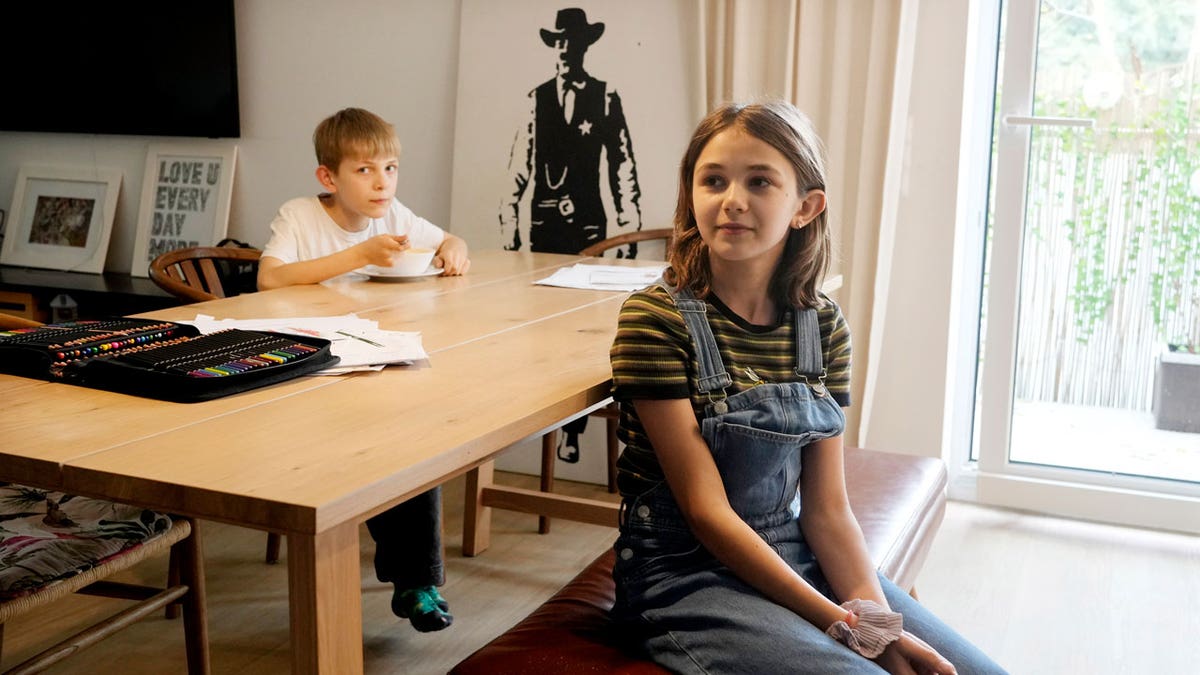 Ola Kozak, 11, right, and her younger brother Julian Kozak, 9, sit at the table where they used to do their homework at their family home