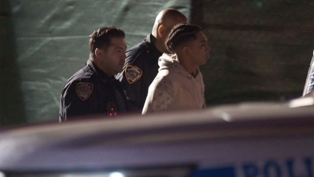 A man is taken away from a migrant shelter in handcuffs on Randalls Island