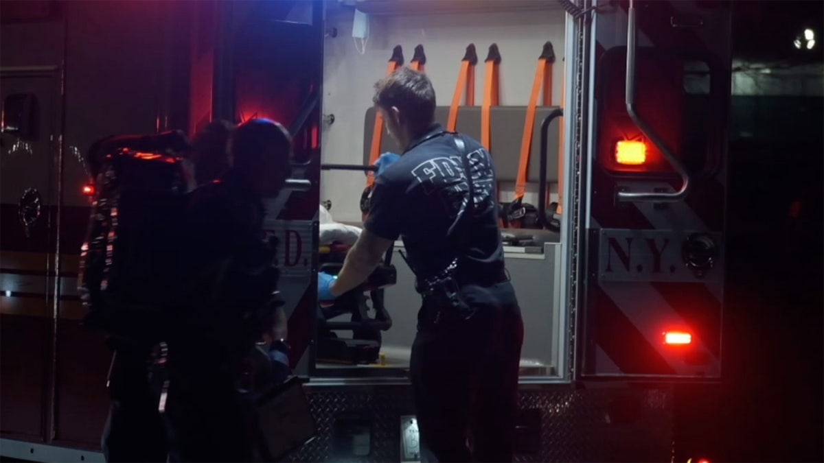 A woman is placed in the back of an ambulance outside of a migrant shelter on Randall's Island